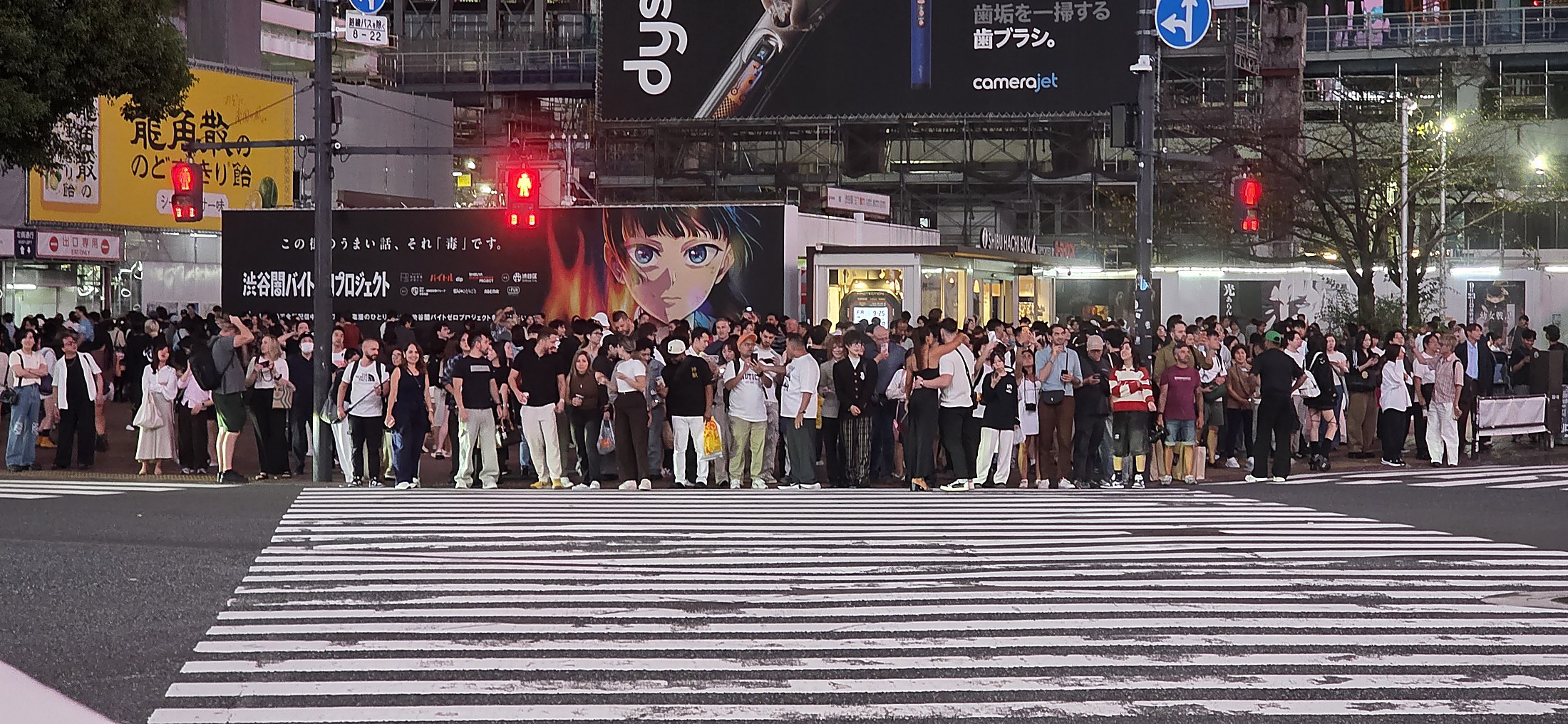 Menschenmenge vor beleuchteter Kreuzung in Tokio bei Nacht