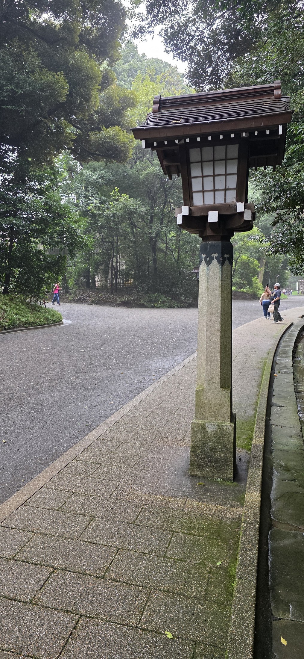 Traditionelle japanische Laterne in Parkanlage mit Spaziergängern